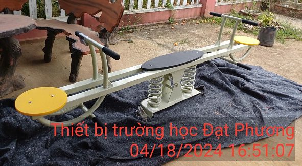 báo giá đồ chơi ngoài trời mầm non.: Sản phẩm bập bênh 2 chỗ Đạt Phương được sản xuất từ vật liệu bền vững, chịu được thời tiết khắc nghiệt. Thiết kế tuân thủ nghiêm ngặt quy định: tay cầm chắc chắn, chỗ ngồi phù hợp lứa tuổi và cách mặt đất tối đa 200mm (nhà trẻ) hoặc 300mm (mẫu giáo) để đảm bảo an toàn tuyệt đối cho bé. Hệ thống chống lật ngang, lật dọc giúp trẻ vui chơi vận động tự tin trong khuôn viên trường học